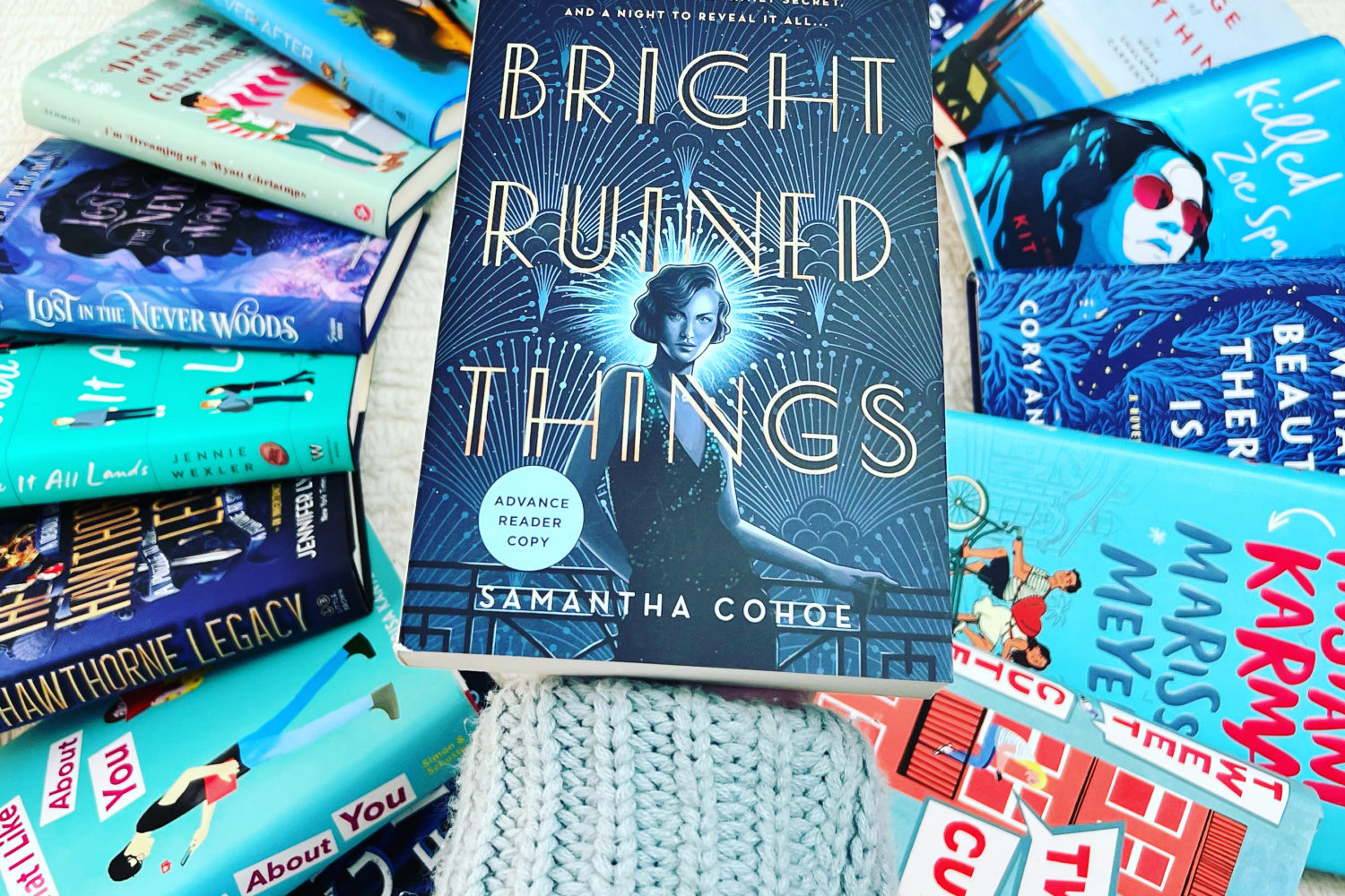 Photo of a book being held over a pile of books. Example of aesthetic bookstagram photo.