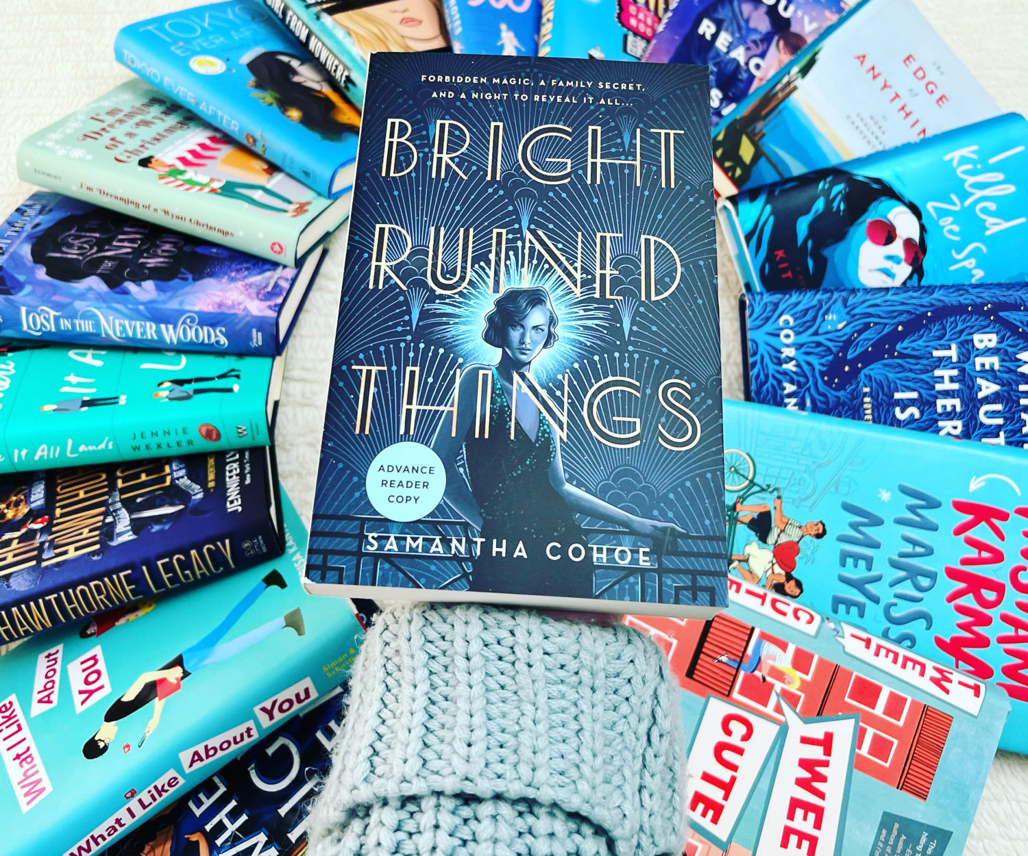 Photo of a book being held over a pile of books. Example of aesthetic bookstagram photo.