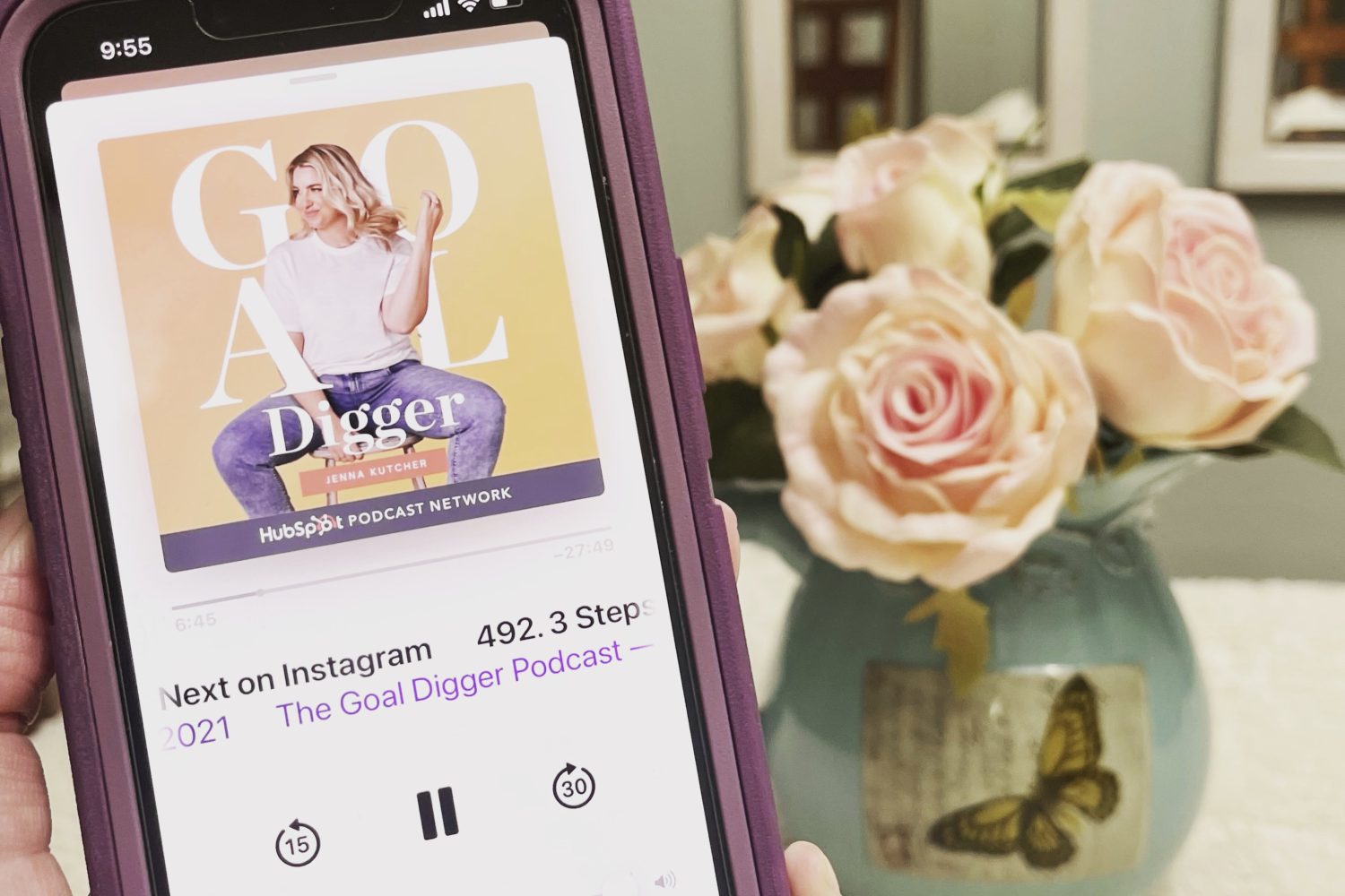 A person holding a phone with an image of the Goal Digger Podcast on it