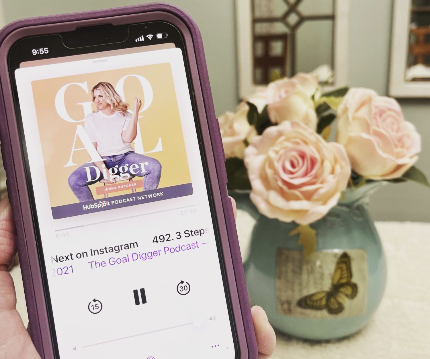 A person holding a phone with an image of the Goal Digger Podcast on it