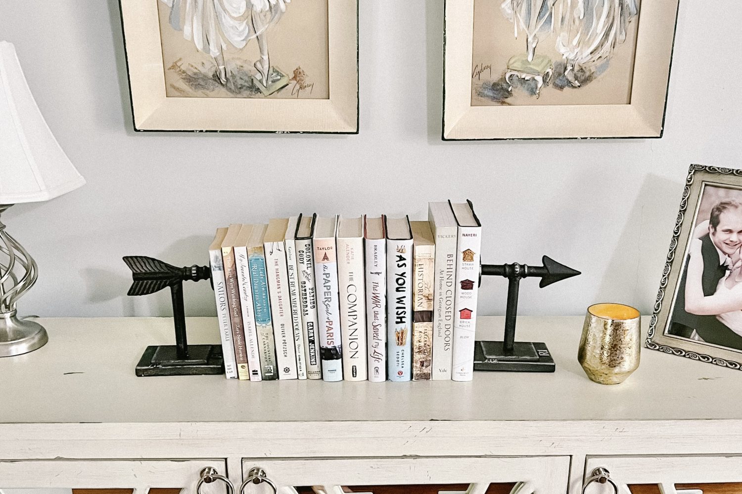A Pair of arrow bookends with a stack of books on a credenza