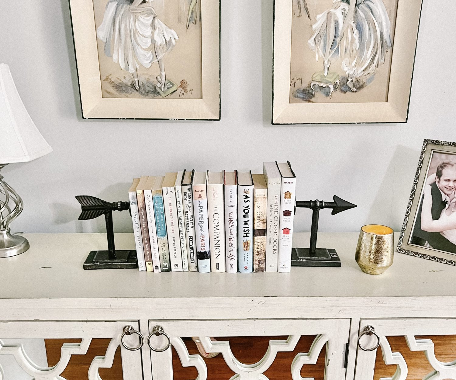 A Pair of arrow bookends with a stack of books on a credenza