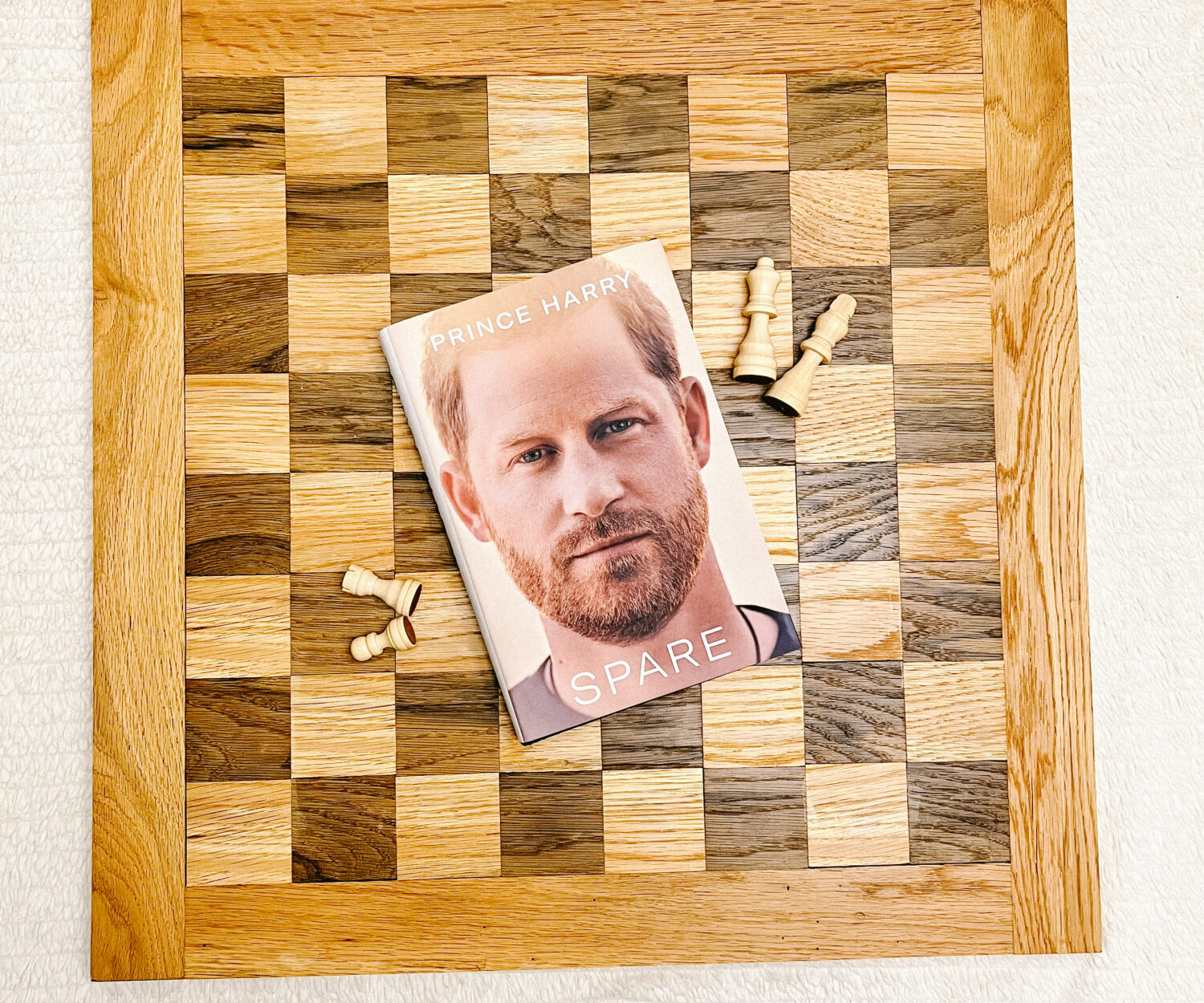 Book cover of Spare by Prince Harry on a chess board