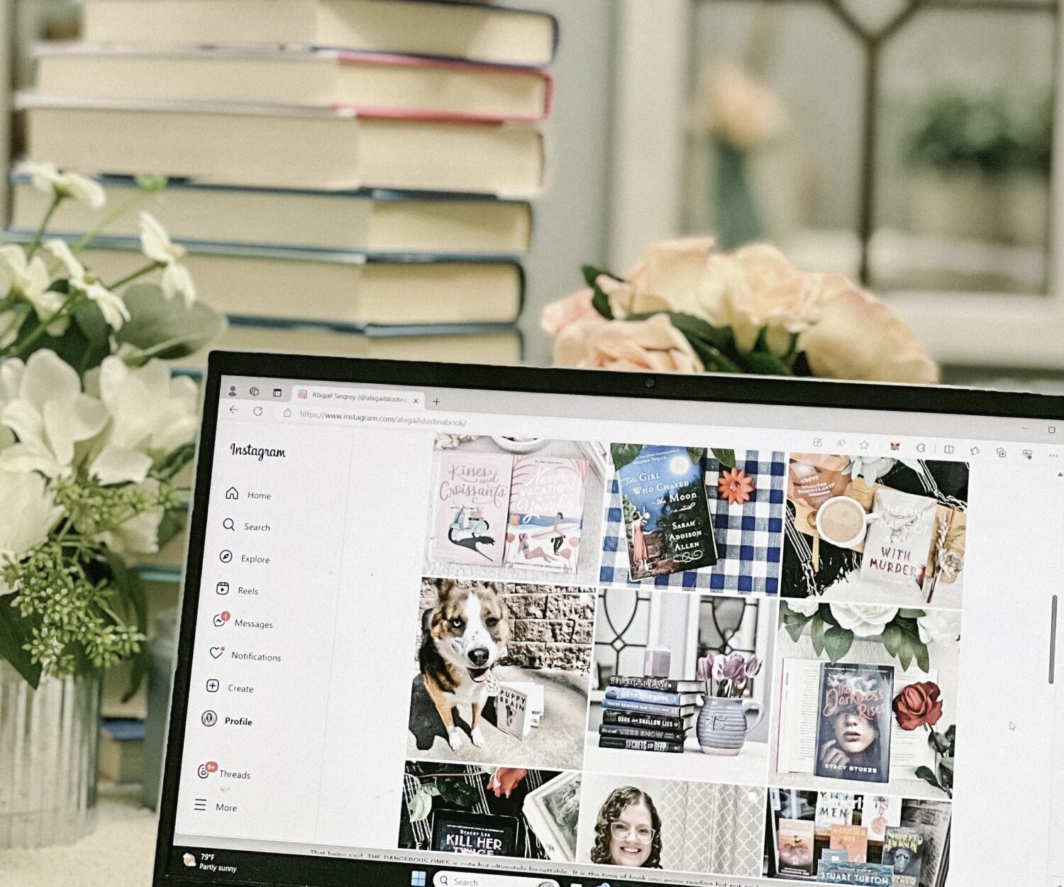 A laptop displaying a bookstagram account in front of a pile of books.